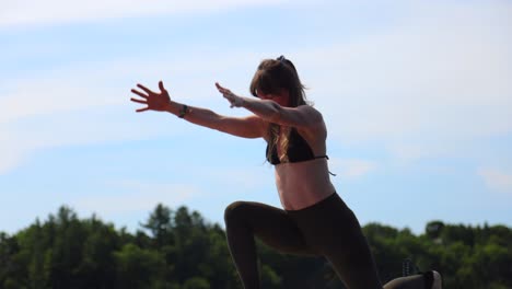 mujer en forma de yoga en paddle board levantando los brazos para estirar slomo fitness
