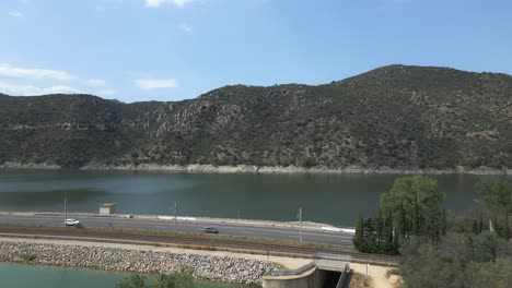 a peaceful area showcasing the lush greenery along the riverbank, with mountains in the background under a bright blue sky on a sunny day. ideal for outdoor exploration