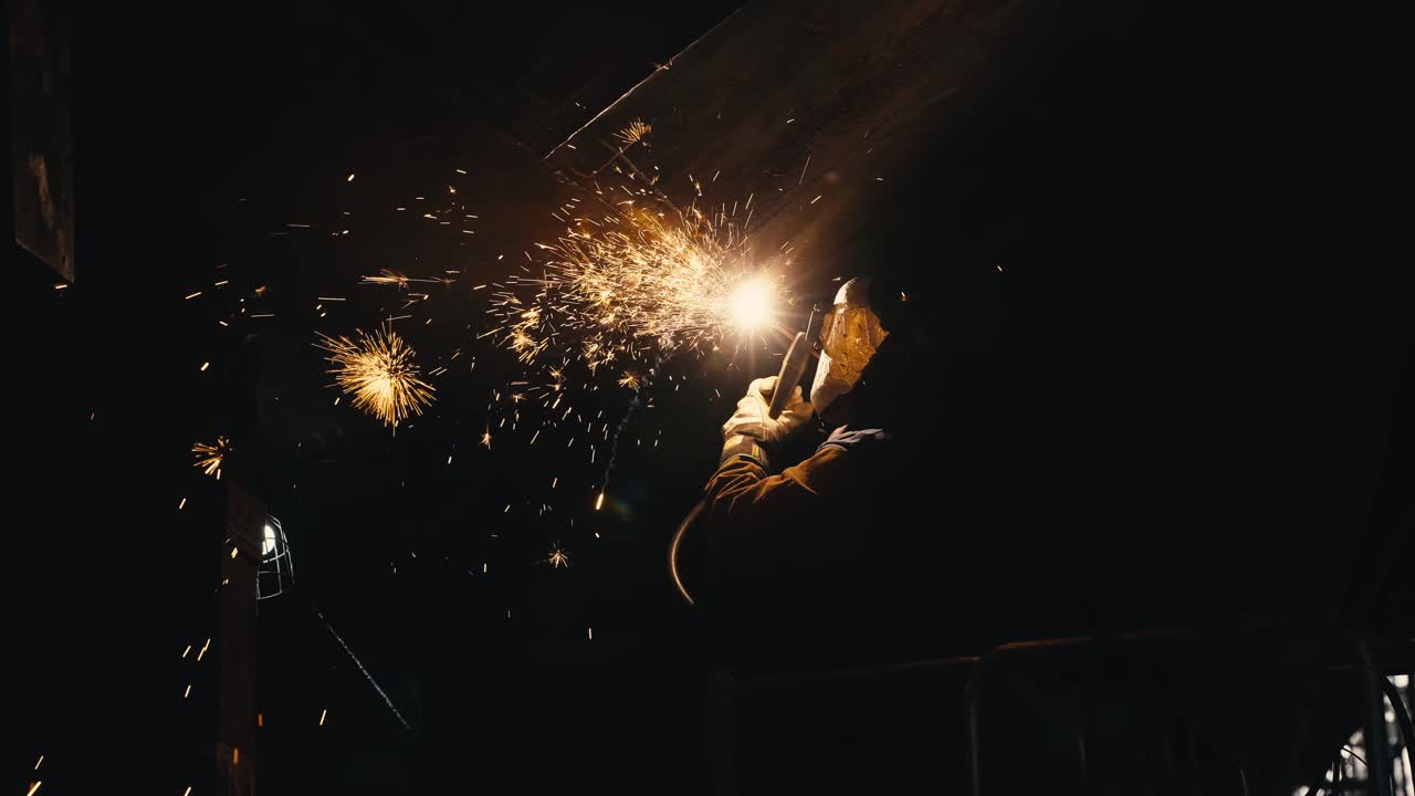 medium tight shot of a man welding metal together on an old ship with sparks flying everywhere