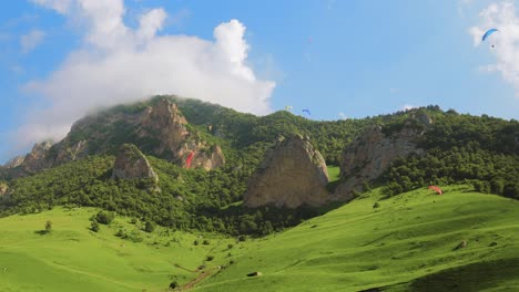 los pilotos de parapente vuelan parapentes entre nubes y montañas verdes.