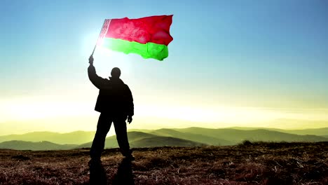 hombre ganador de silueta exitosa agitando la bandera de bielorrusia en la cima del pico de la montaña. fondo de bucle de cinemagraph