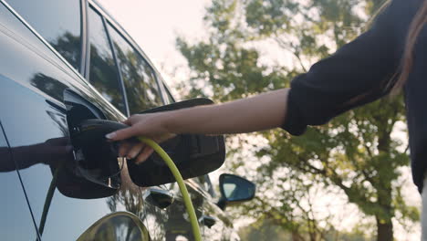 hand plugging in a charger in the electric car charging socket, low angle shot