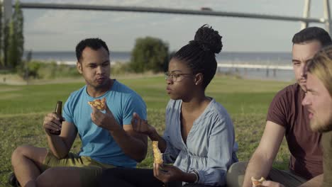 Side-view-of-serious-friends-having-picnic-in-park