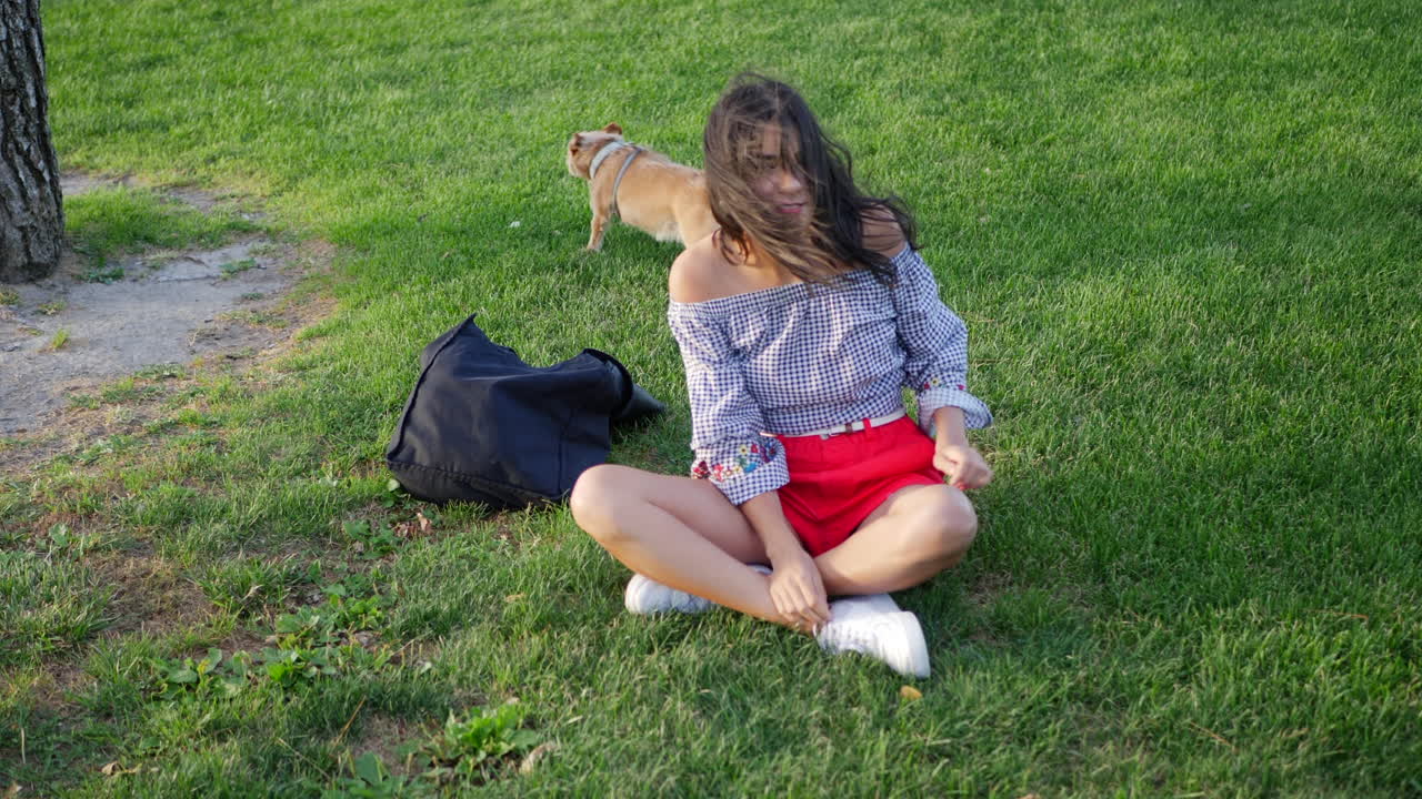una linda joven hispana y su pequeño perro mascota jugando juntos en un campo del parque
