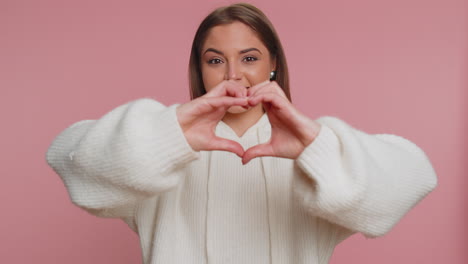 una hermosa mujer sonriente hace un gesto de corazón demuestra un signo de amor expresa buenos sentimientos y simpatía