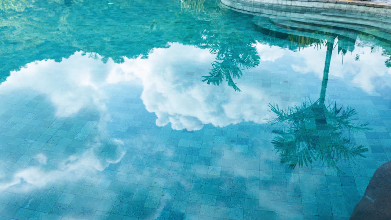 timelapse of luxury swimming pool set with reflections of clouds in the water