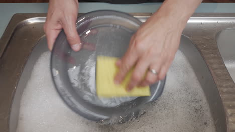 While-male-washing-a-plastic-plate-in-a-sink