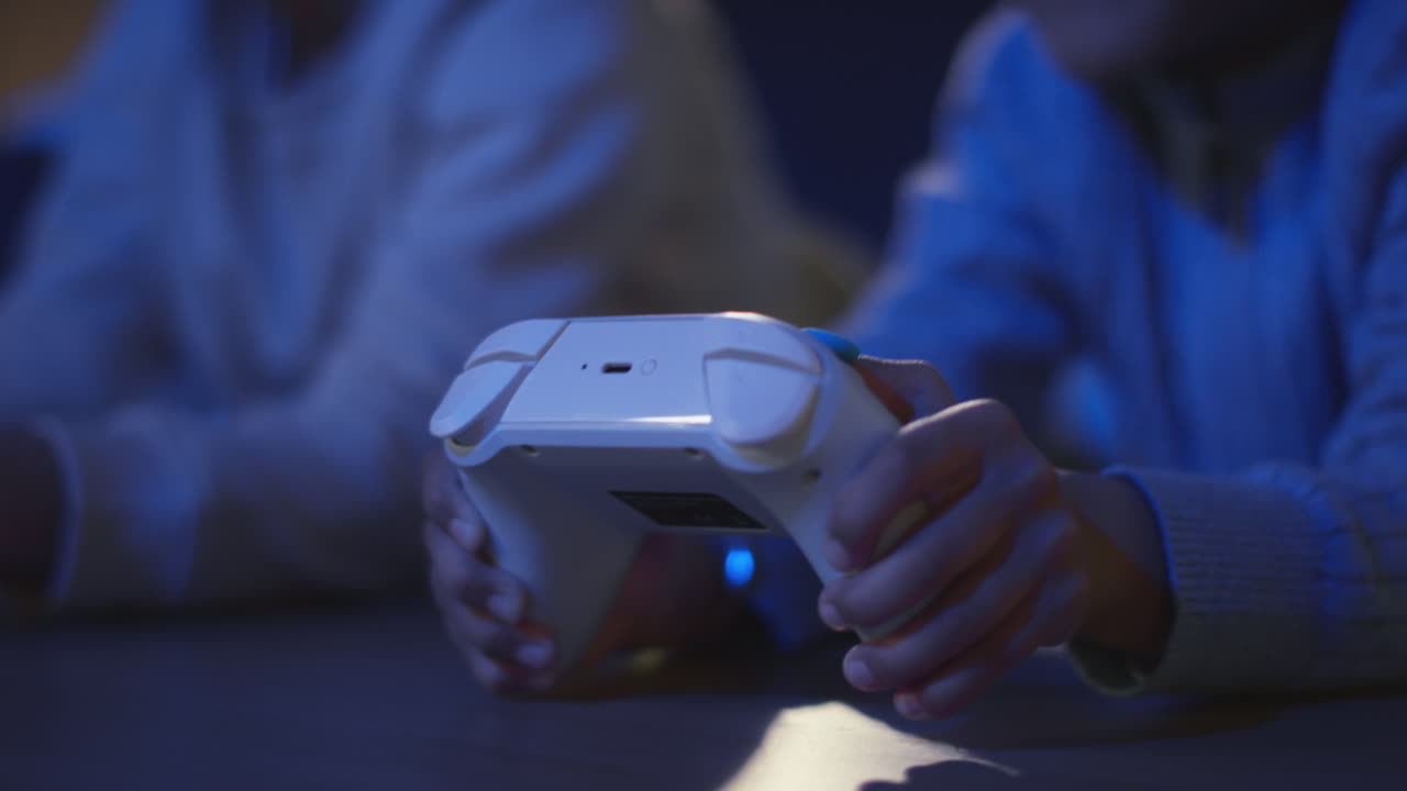Close Up Of Two Young Boys At Home Playing With Computer Games Console On TV Holding Controllers Late At Night 6