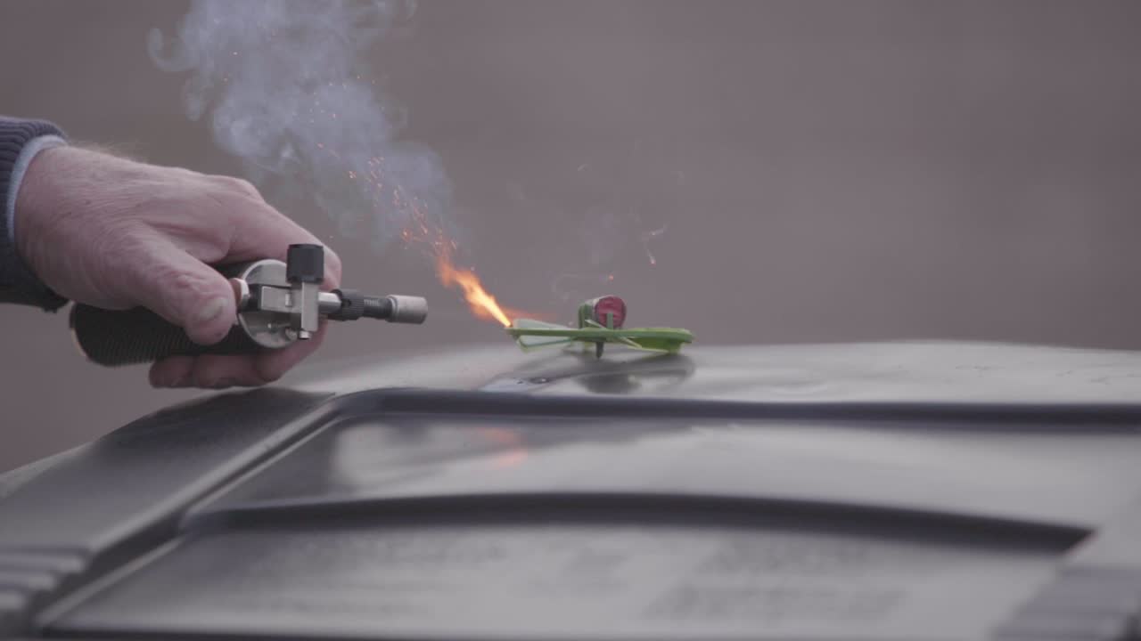 Lighting an areal firework with a mini blow torch.  the fuse ignites and begins to burn