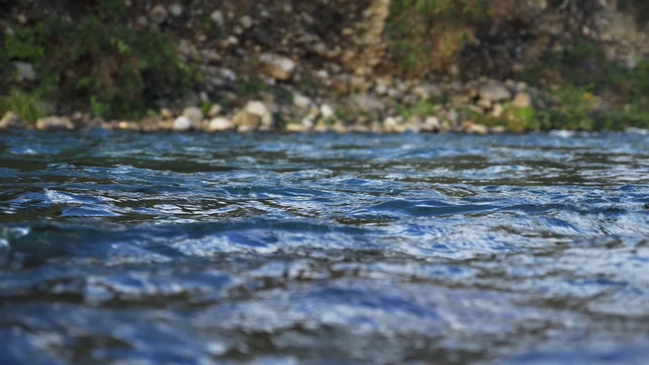 Sfondo naturale: Fiume selvaggio blu scuro e riva rocciosa, medio
