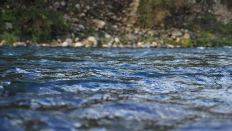 natural dark blue wild river and rocky shore background, medium