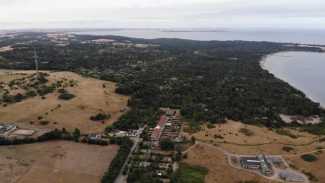 Aerial-view-of-the-coastline-of-SejerÃ¸bugten-with-hills,-fields-and-ocean