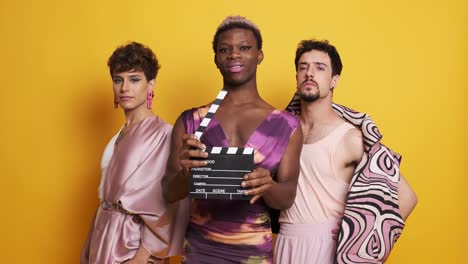 three transgender male models posing with a film clapperboard