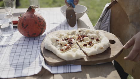 cutting a homemade pizza outdoors