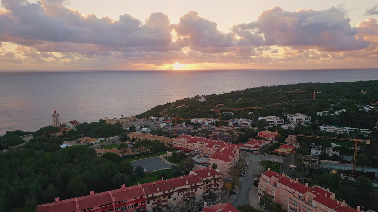Coastal city bathed sunset glow near lighthouse. Aerial view tranquil seascape