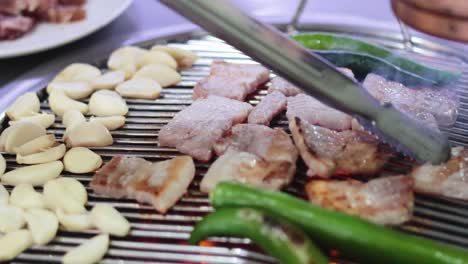 cooking pork belly on a grill with garlic and green peppers.