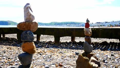 colourful rocks arrangement balanced on sunny llandudno beach seaside promenade shoreline dolly left