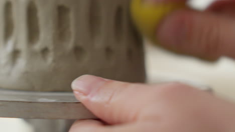 usando una esponja sobre arcilla suave, el artesano mezcla a la perfección los lados de la taza, mostrando un toque exquisito y artesanía