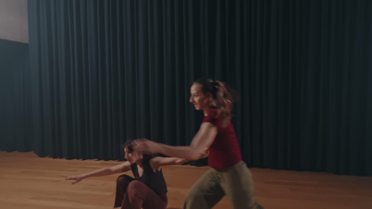 two women perform contemporary duet with expressive movement on stage