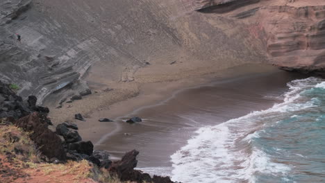 toma amplia en cámara lenta de la playa de arena verde papakolea con olas rompientes durante el día soleado