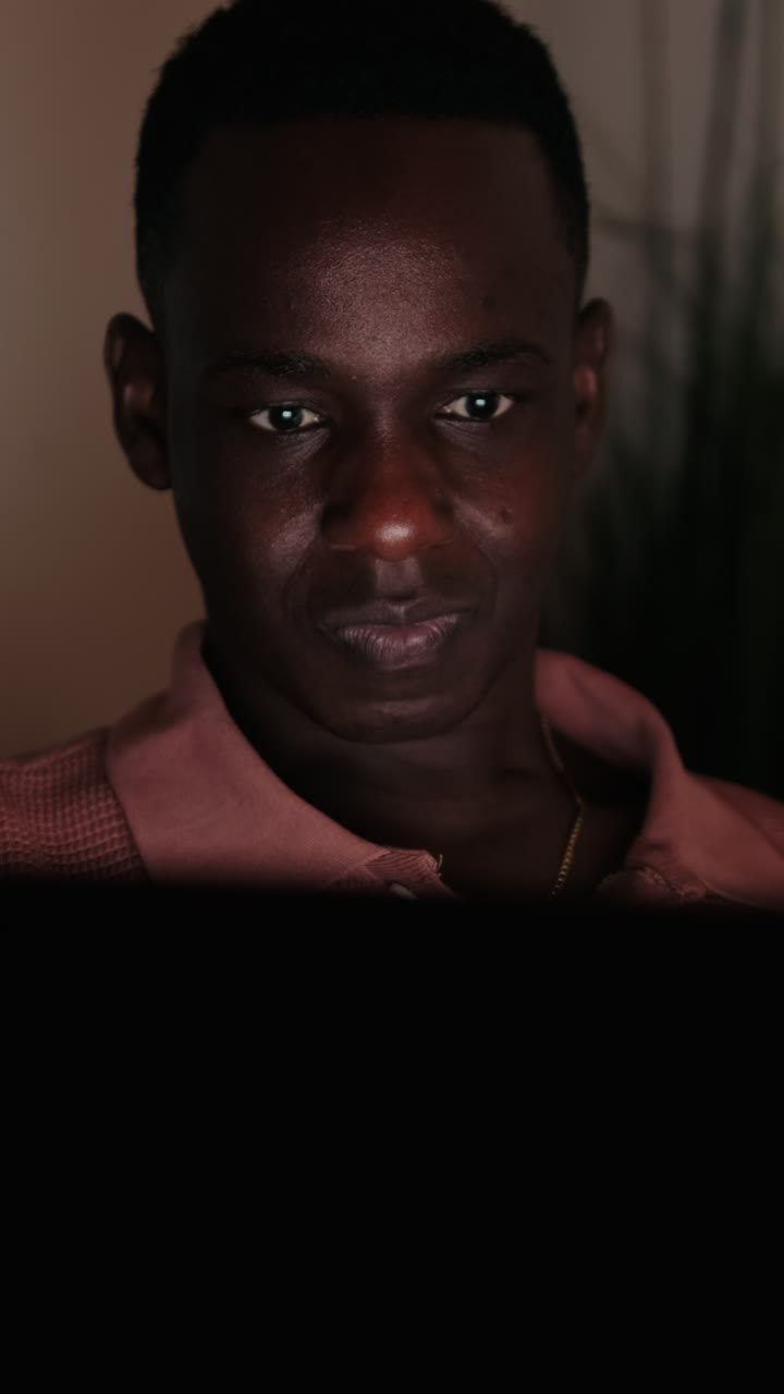 Young Black Man Smiling While Looking at a Screen