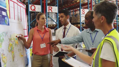 warehouse staff in discussion at an information board 4k