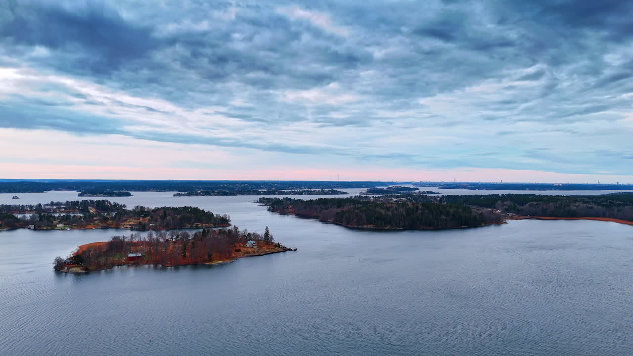 Aerial view of islands in Stockholm archipelago under cloudy sky. High angle shot of forested islands and calm water in the Swedish archipelago during overcast weather