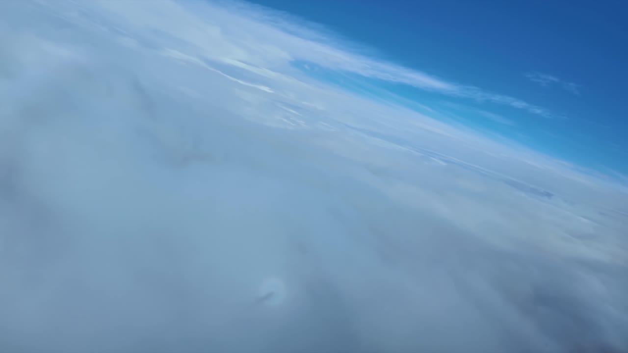 Aerial view from a jet airplane cockpit of the shadow of the plane on the clouds, with the nose inside a full rainbow (Anthelion effect)