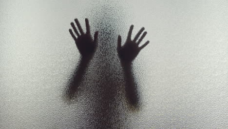 A female silhouette behind the frosted window touches the glass slowly