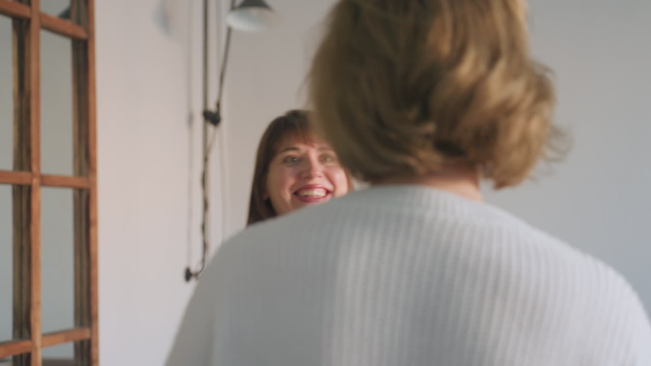 Cheerful mental health professional in navy dress warmly welcomes lady into session with bright smile and eye contact, showing friendly supportive interaction in comfortable counseling environment