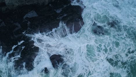 top-down-aerial-of-waves-crashing-against-rocks