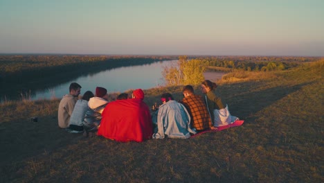 Fröhliche-Freunde-Unterhalten-Sich-Abends-Am-Brennenden-Lagerfeuer