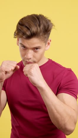 man in fighting stance with clenched fists on a yellow background