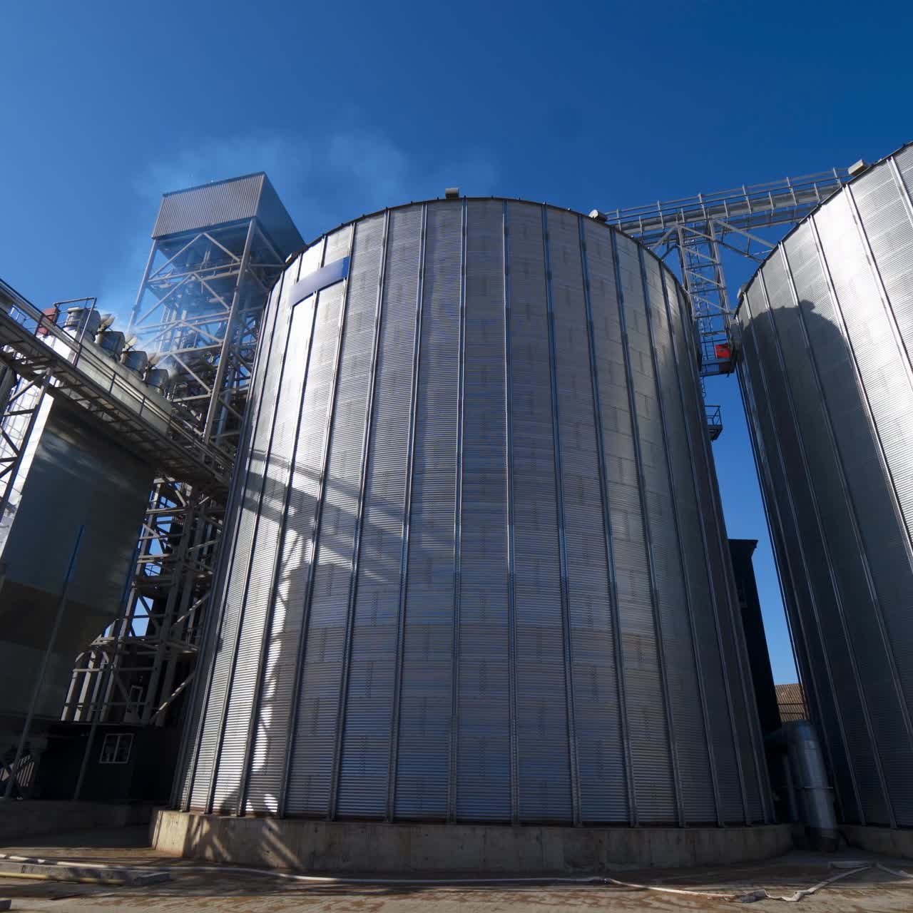 Exterior of grain elevators on field. Large granary of a modern industrial plant for agriculture. Industrial complex for storage crop