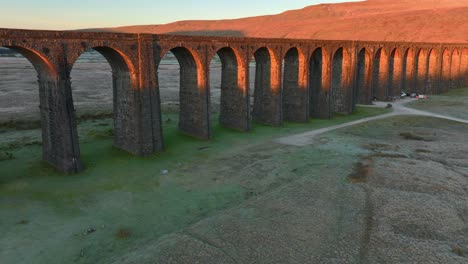 los arcos del puente ferroviario atrapan la luz del amanecer de invierno y la colina iluminada