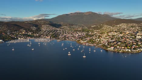 descending aerial view of hobart and the derwent river at sunset. mountains in the background.