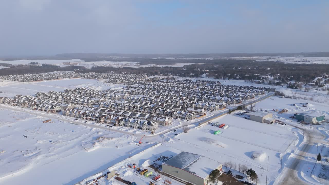 Vista aerea con drone di un nuovo sviluppo residenziale coperto di neve a Erin, Ontario, che mostra un grande quartiere residenziale, file di case moderne, strade invernali e una comunità suburbana in espansione.