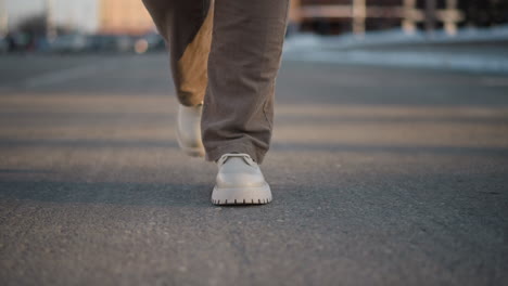 leg view of snow dancer performing rhythmic tap dance on cracked pavement during sunny winter day, white boots in motion, capturing energy of expressive street performance from low angle perspective