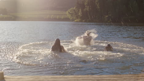 happy friends running jumping off jetty in lake at sunset having fun splashing in water enjoying freedom sharing summertime adventure