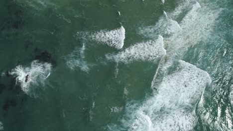 Aerial-view-of-the-blue-waves-near-the-coast-of-a-beautiful-tropical-island