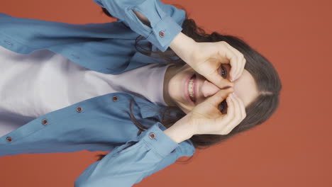 vertical video of young woman with binoculars looking away.