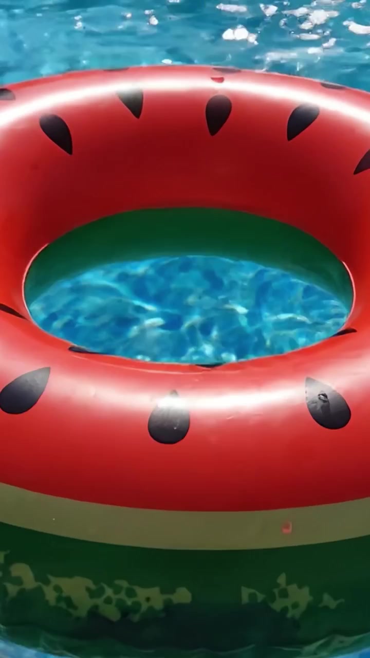 A Vibrant Watermelon Float Ring Sitting in a Crystal Clear Swimming Pool, Capturing the Essence of Summer Fun and Relaxation Under the Bright Sunlight