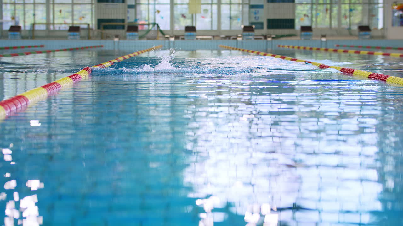 vista frontal de un atleta nadando estilo de pecho en la piscina