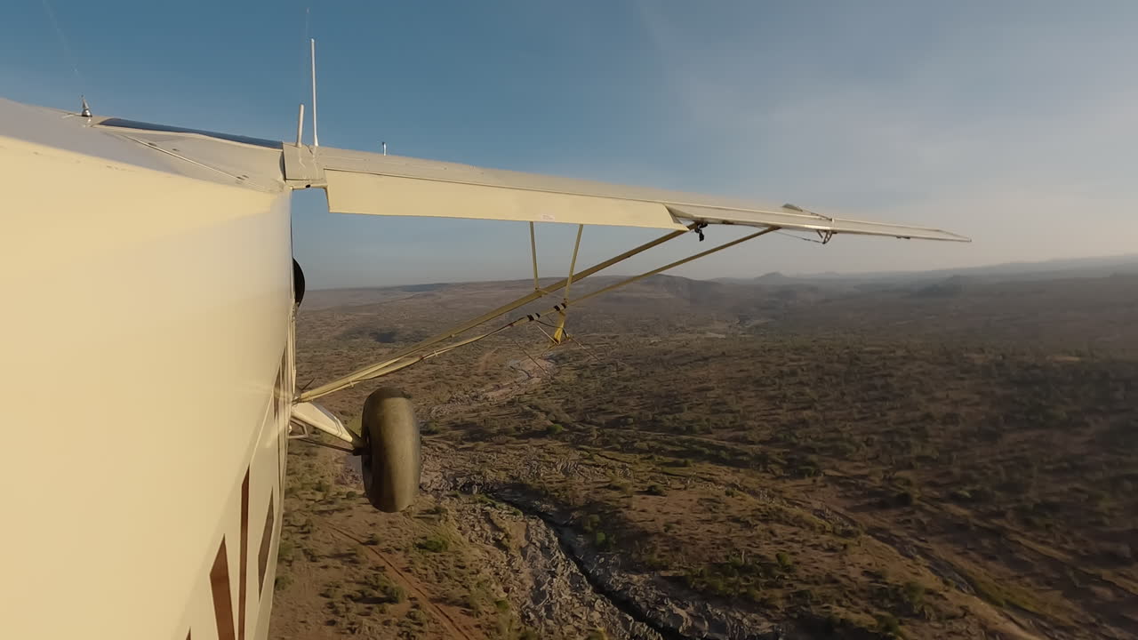 Seitenansicht eines kleinen Flugzeugs über Sträuchern, Fluss und Straße