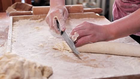 woman, housewife, cuts the roll of dough into thin strips with a knife