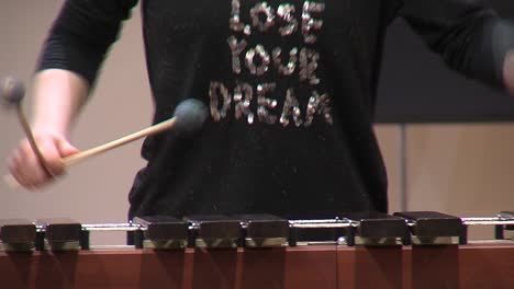 pan shot of musician playing marimba instrument with mallets on performance