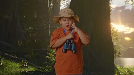 niño asiático con sombrero y binoculares hablando en teléfono inteligente mientras explora la naturaleza forestal. niño investigador examina algo, concepto de aventura de turismo de viaje