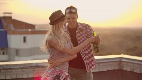 una pareja americana en camisas a cuadros baila en el techo. una chica con cerveza girando en el baile con su novio.