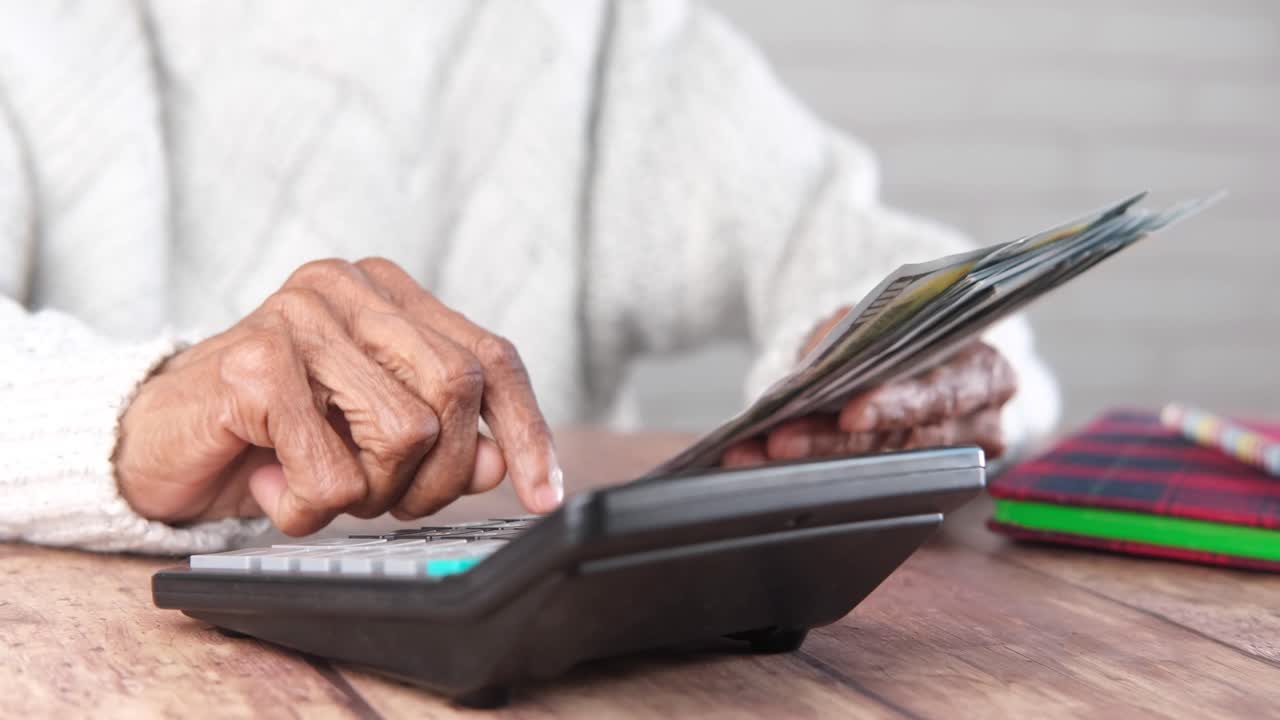 persona mayor contando dinero y usando una calculadora