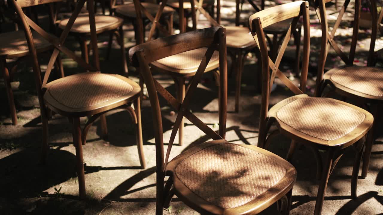 wooden chairs with woven seats bathed in sunlight at an outdoor ceremony setup